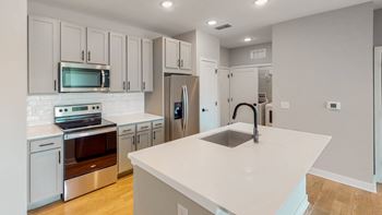 a kitchen with white cabinets and a large white island with a sink  at Ironwood Flats, Brandon, FL, 33511